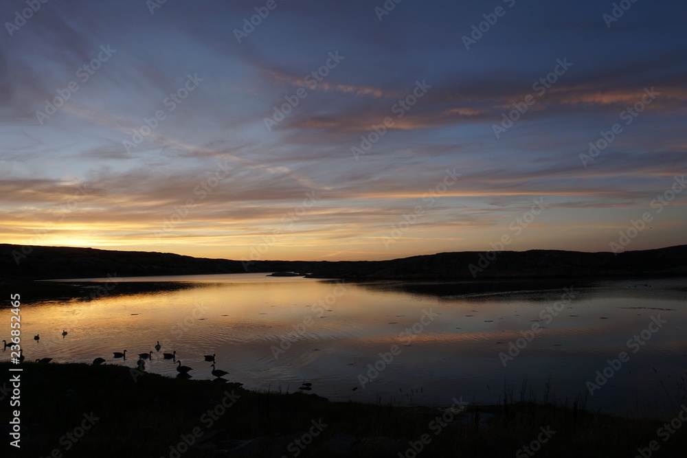 sunset over lake in Sweden in summer with orange sky