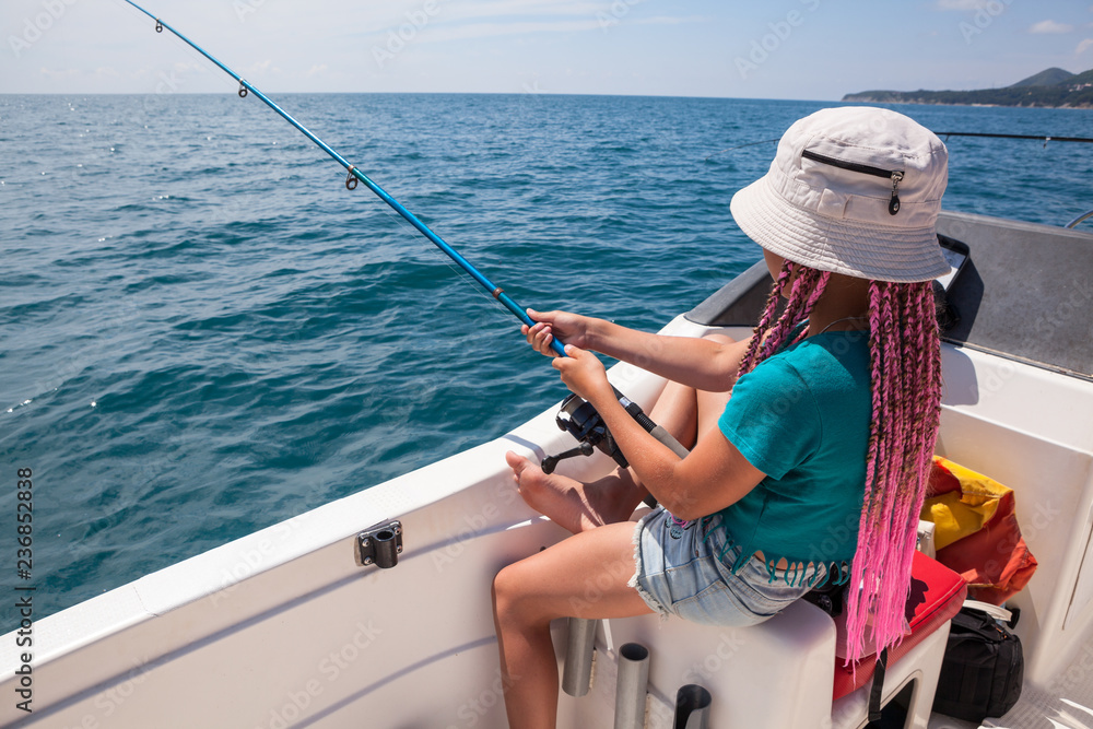 One pretty girl have fishing on sailboat, deep-sea fishing trip, holding  rod in hands Stock Photo