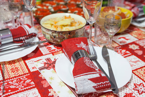 White plate with knif, fork and red tissue napkin are on festive table