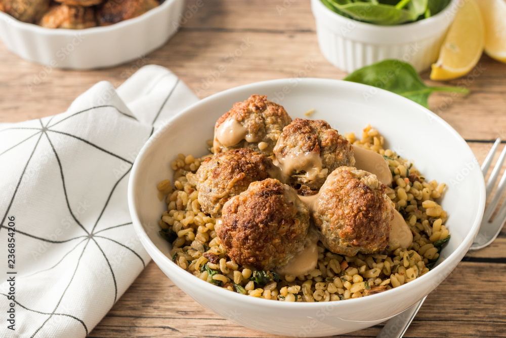 Spicy meatballs with spinach and bulgur in white bowl on wooden kitchen table. Spicy meatballs with spinach and bulgur in white bowl on wooden kitchen table.