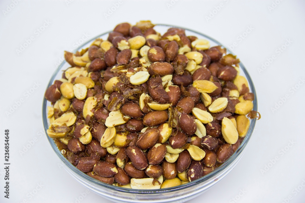 Roasted peanuts in glass bowl on white background Roasted peanuts in glass bowl on white background