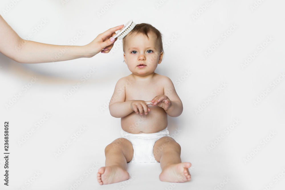 Young mother is brushing a hair of a newborn. Mother is teasing baby hair with hairbrush. Baby care, healthcare concept Young mother is brushing a hair of a newborn. Mother is teasing baby hair with hairbrush. Baby care, healthcare concept