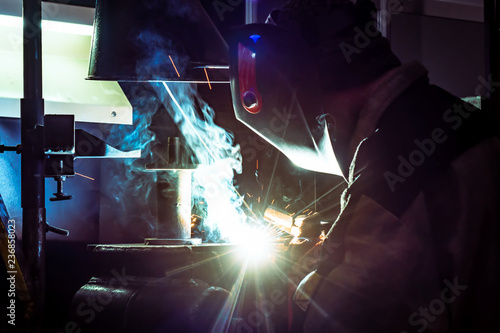 The welder does the work. Man at work. Welding work. Welder costume. Working. Welding mask. Welding electrodes. Ventilation in production. Harmful work. Welding equipment.