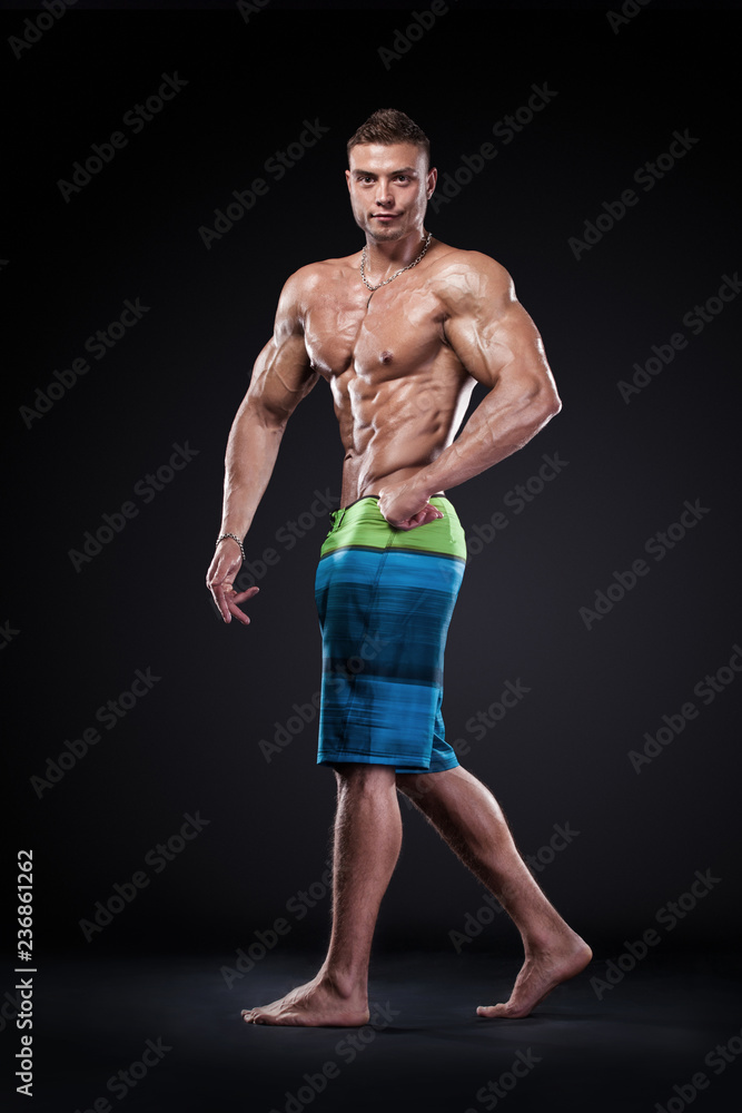 Bodybuilding competitions on the scene. Man sportsmen physique and athlete. Black background with lights.