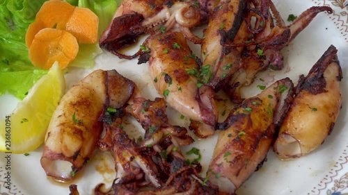 Grilled and fried seafood on a traditional Mediterranean plate garnished with summer vegetables and fruits - greece, croatia, italy, montenegro, squid.