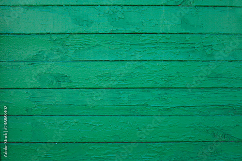 Wooden boards painted in green. Old green background. Painted wood surface. The surface of the wooden green train car. The parallel lines of the boards. The surface of the old fence.