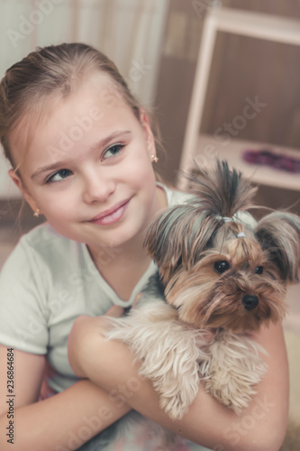 Cute young blonde girl with her Yorkshire terrier puppy playing and hugging