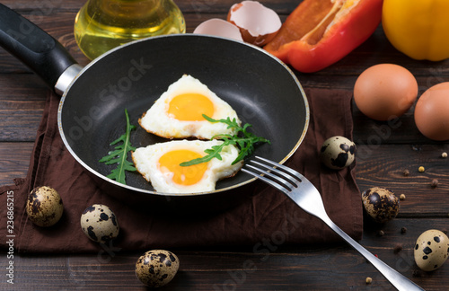 Fried eggs on a skillet on a wooden background