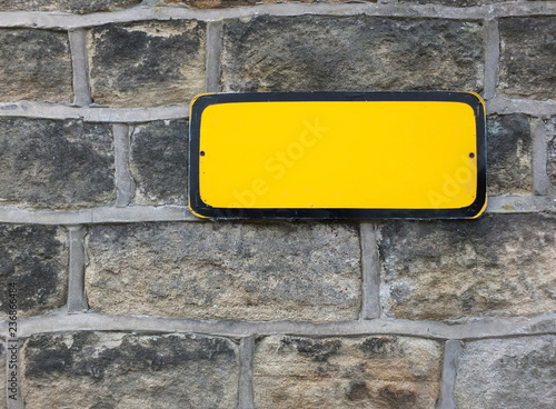 Foto a blank yellow metal sign with empty space for copy on an old stone wall backgro