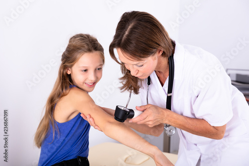 Female Doctor Examining Skin Of Girl photo