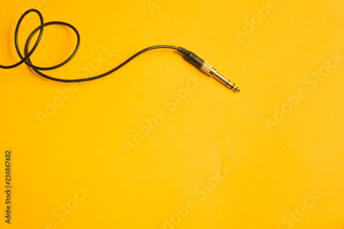 Audio jack with black cable isolated on yellow background