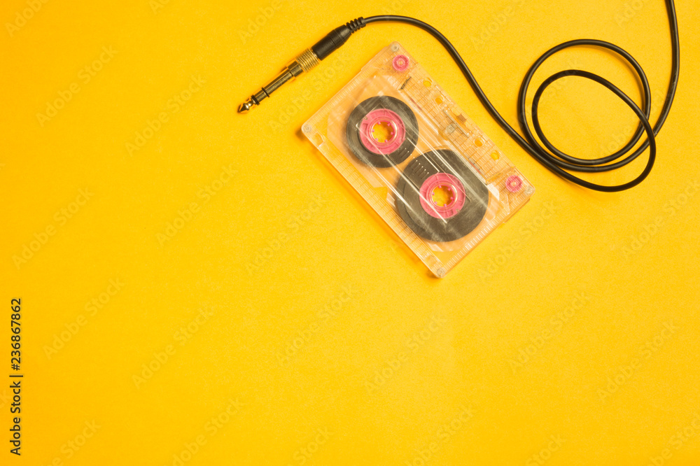 Retro cassette tape and audio jack on the yellow background. copy space Retro cassette tape and audio jack on the yellow background. copy space