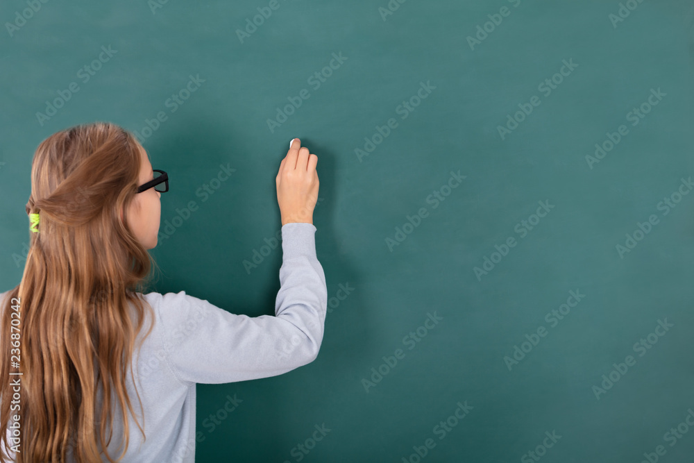 Female Student Writing With Chalk On Chalkboard Female Student Writing With Chalk On Chalkboard