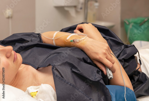 The woman in a delivery room with a dropper and presses the remote button for a regular dose of epidural anesthesia