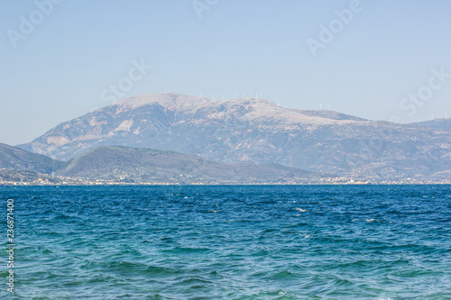 summer traveling concept of sea shore line vivid blue and green water waves surface and mountain horizon background landscape 