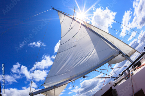 Photo of a sail with the sun shining in the form of a star under a beautiful blue sky