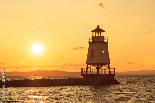 A beautiful orange sunset behind a lighthouse in front of Burlington Vermont