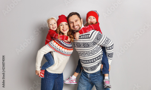 happy family mother, father and children in knitted hats and sweaters on gray background