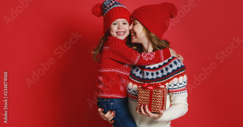 happy family mother and child daughter with christmas gifts on red background