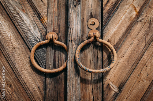 Fototapeta Naklejka Na Ścianę i Meble -  Round metal handles on closed old antique wooden  gate or door
