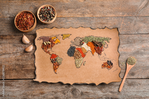 Paper with world map made of different aromatic spices on wooden background, flat lay
