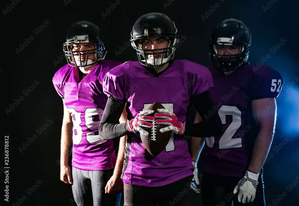 American football players in uniform on dark background