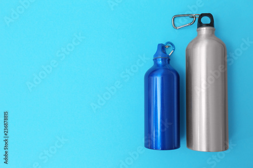 Sport bottles with space for text on color background, top view
