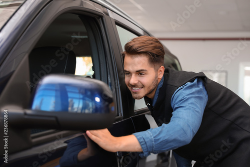 Young man near new car in dealership © New Africa