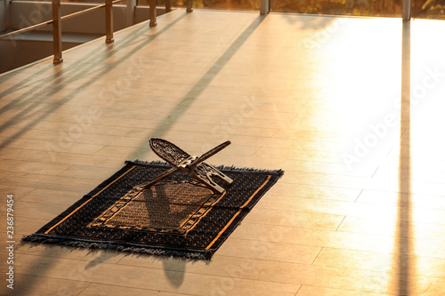 Rehal on Muslim prayer mat indoors. Space for text