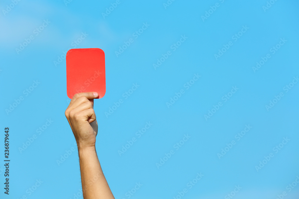 Fototapeta premium Football referee showing red card against blue sky, closeup with space for text