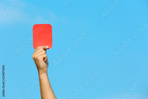 Football referee showing red card against blue sky, closeup with space for text