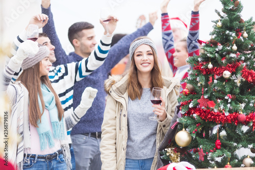 Young woman with friends toasting for Christmas on balcony