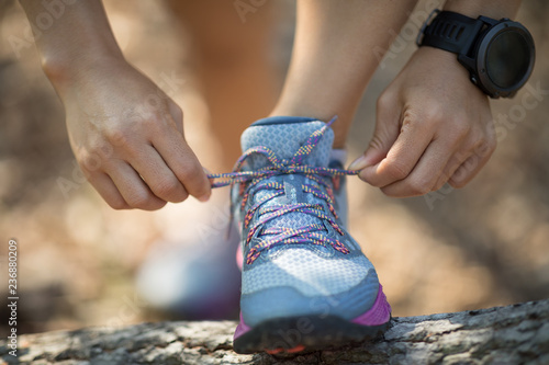 Sportswoman trail runner tying shoelace in forest