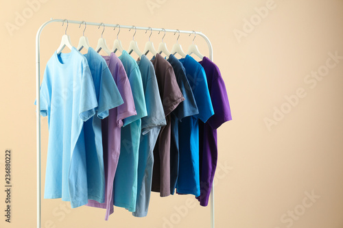 Men's clothes hanging on wardrobe rack against light background