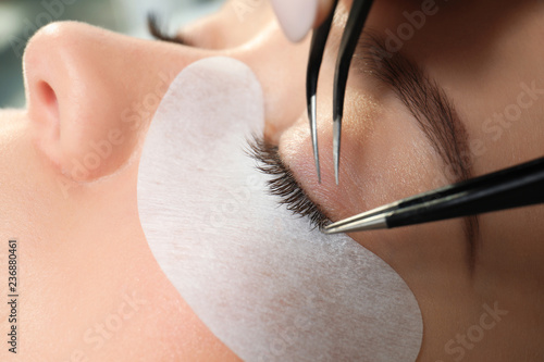 Young woman undergoing eyelash extension procedure, closeup