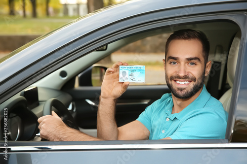 Cuadro en lienzo Young man holding driving license in car