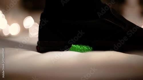 Green plastic christmas ornament being stepped on in slow motion