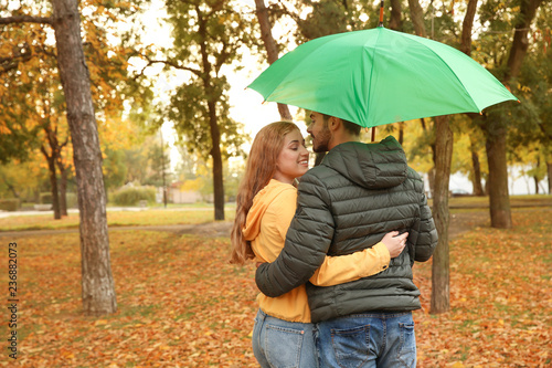 Happy couple with umbrella walking in park. Space for text © New Africa