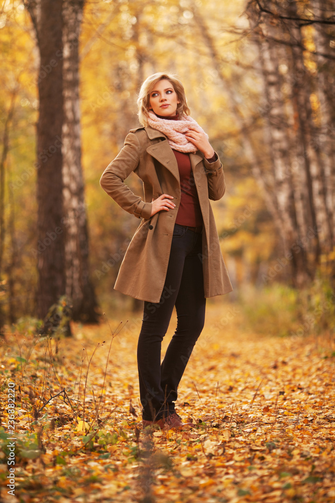 Young blond fashion woman in classic beige coat walking outdoor Young blond fashion woman in classic beige coat walking outdoor