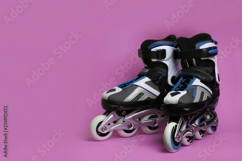 Pair of inline roller skates on color background. Space for text