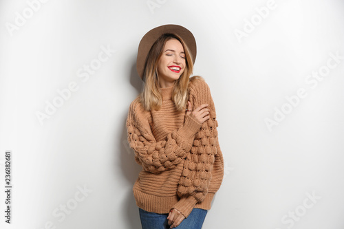 Piękna młoda kobieta w ciepłym pulowerze z kapeluszem na białym tle
