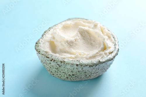 Bowl of tasty cream cheese on color background