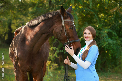 Veterinarian in uniform with beautiful brown horse outdoors
