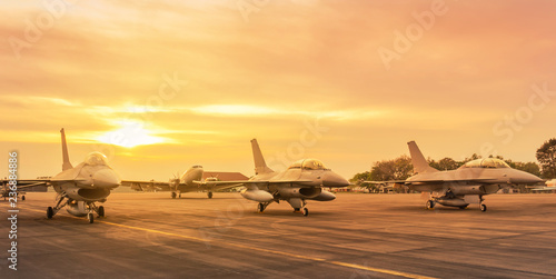 Samolot wojskowy myśliwca Falcon zaparkowany na pasie startowym w gotowości sił powietrznych bazy gotowy do startu na misję wojskową o zachodzie słońca