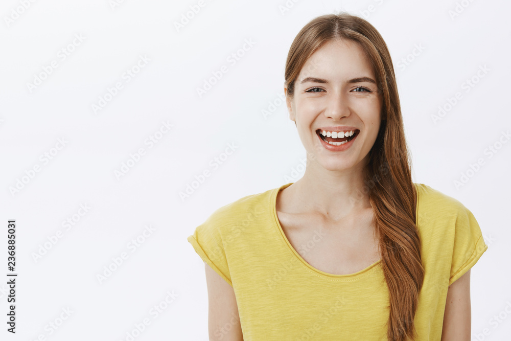 Close-up shot of kind happy charming european woman with braid in yellow birght t-shirt smiling joyfully at camera having fun enjoying nice friendly conversation standing against white background Close-up shot of kind happy charming european woman with braid in yellow birght t-shirt smiling joyfully at camera having fun enjoying nice friendly conversation standing against white background