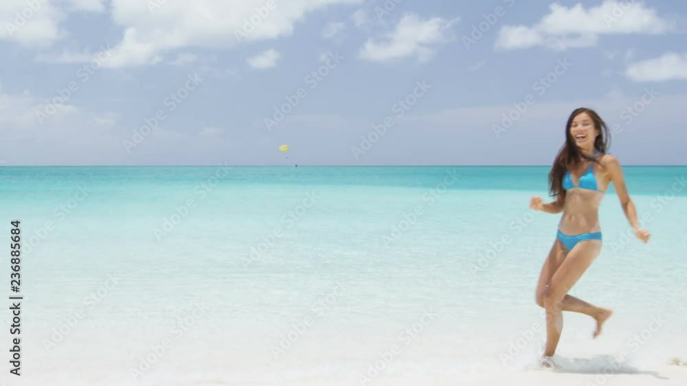 Travel Vacation. Excited young woman in white bikini running on beach. Cheerful female is enjoying nature during her summer vacation. Scenic view of seascape against sky. Travel Vacation. Excited young woman in white bikini running on beach. Cheerful female is enjoying nature during her summer vacation. Scenic view of seascape against sky.