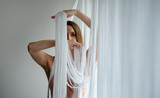 Portrait einer wunderschönen jungen attraktiven sexy Frau, nackt teilweise dekorativ von den weißen Fäden eines Fadenvorhang verdeckt bewegt tänzerisch ihre Hände