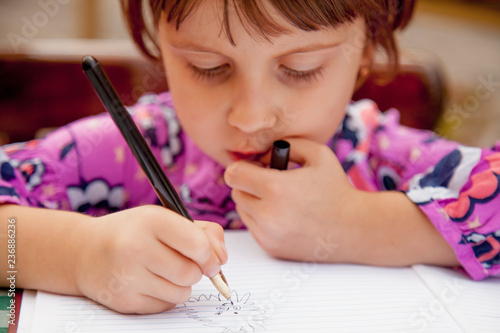 Humorous portrait of little female artist designer draws a pencil sketch  on notebook  creativity  art  training concept 