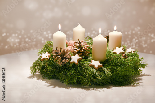 Third Advent - decorated Advent wreath from fir and evergreen branches with white burning candles, tradition in the time before Christmas, warm background with festive bokeh and copy space