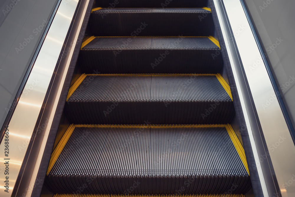 Empty escalator or moving stair. Also called stairway or staircase. Modern architecture design with step, glass for lift people up floor building i.e. shopping mall, airport, metro and subway station. Empty escalator or moving stair. Also called stairway or staircase. Modern architecture design with step, glass for lift people up floor building i.e. shopping mall, airport, metro and subway station.